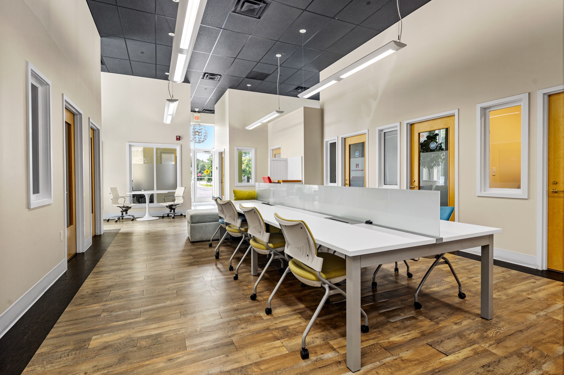 The coworking area at Workspace Cohasset with shared desks and private offices along both walls