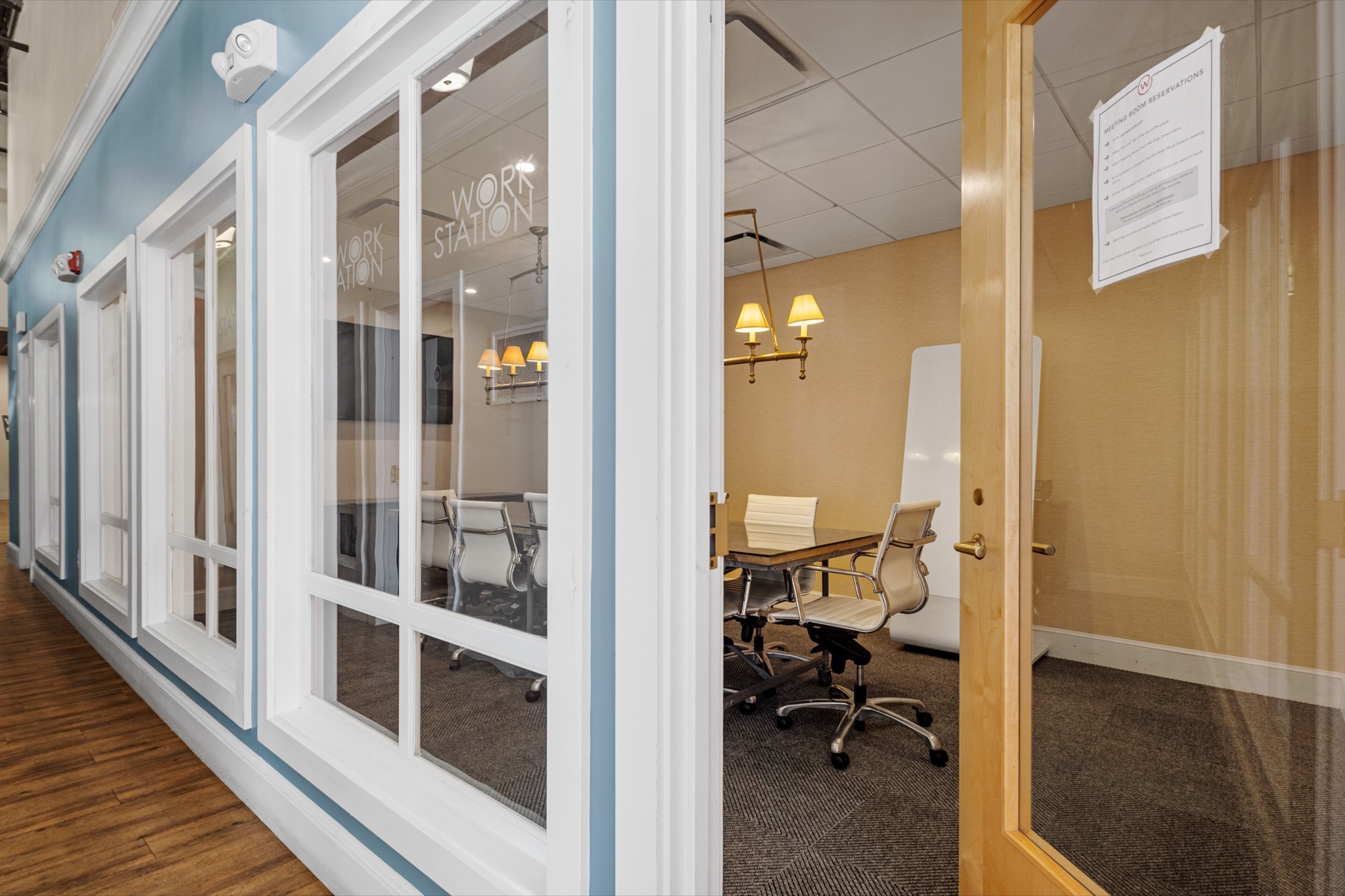 A glass-walled meeting room seen from the hallway at Workspace Cohasset